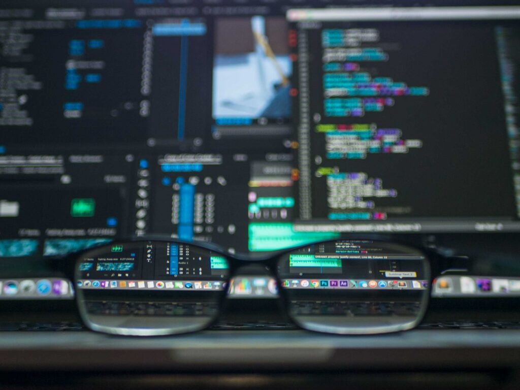 Glasses focusing small portion of a large set of computer monitors with coding tools and applications open